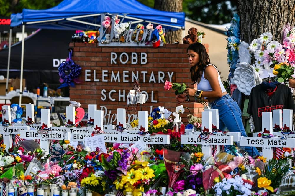 A girl lays flowers at a makeshift memorial at Robb Elementary School in Uvalde, Texas in May 2022