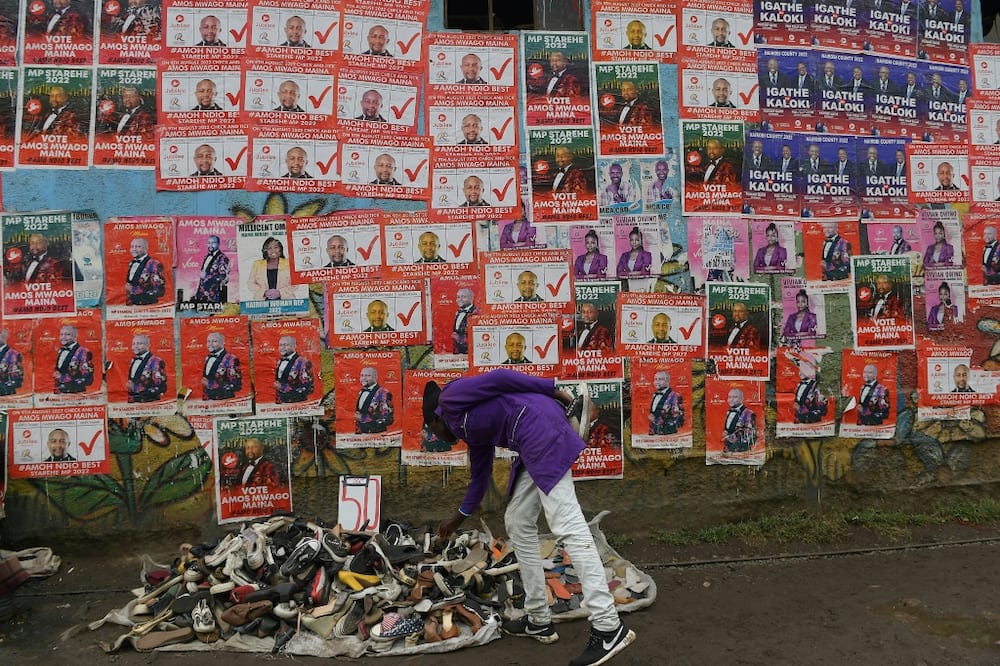 A hawker in Nairobi sells second-hand shoes next to campaign posters of various candidates ahead of the August 9 election