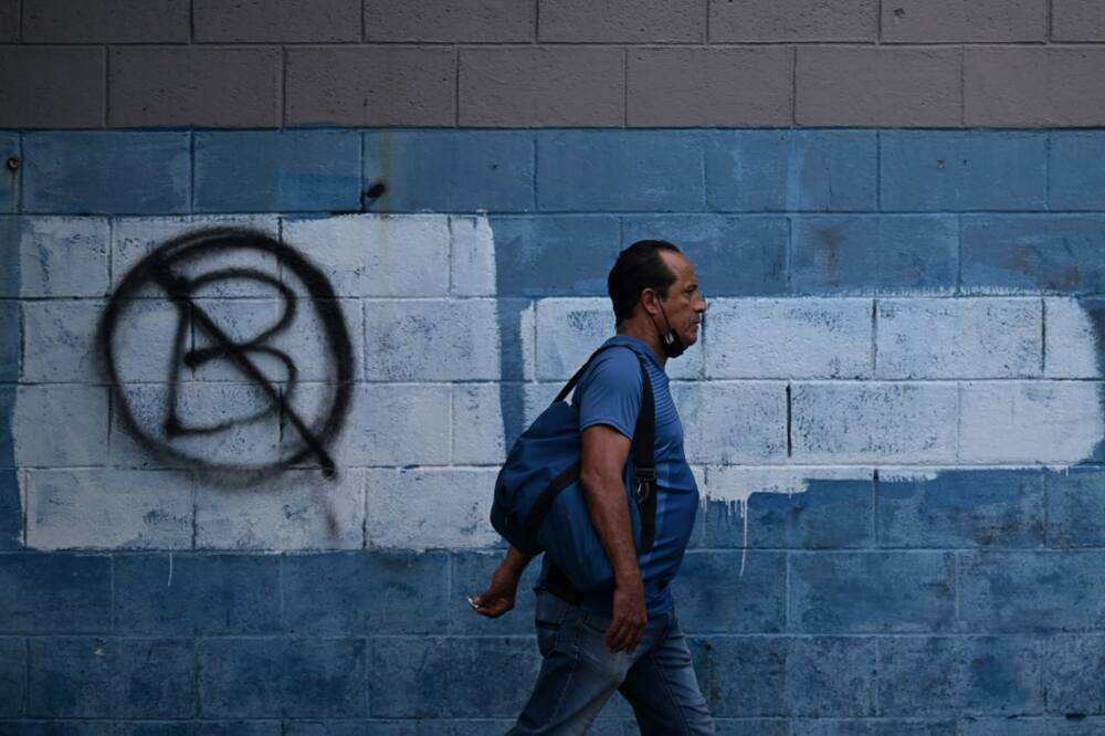 A man walks past a wall painted with an anti-Bitcoin protest symbol, in San Salvador, on October 18, 2022. Most Salvadorans have not used bitcoin so far this year and consider it a failure, a poll showed.
