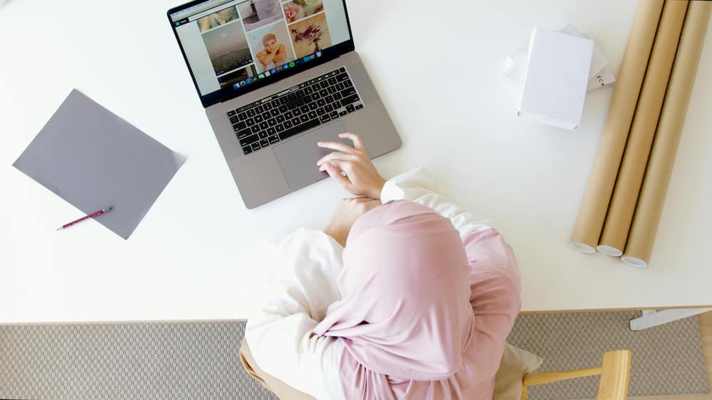 A woman in a pink Hijab using a laptop
