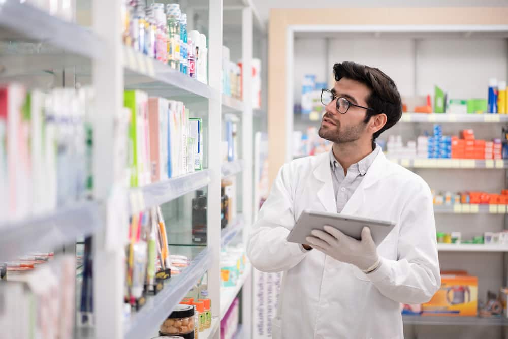 A pharmacist using a digital tablet to do inventory in a pharmacy