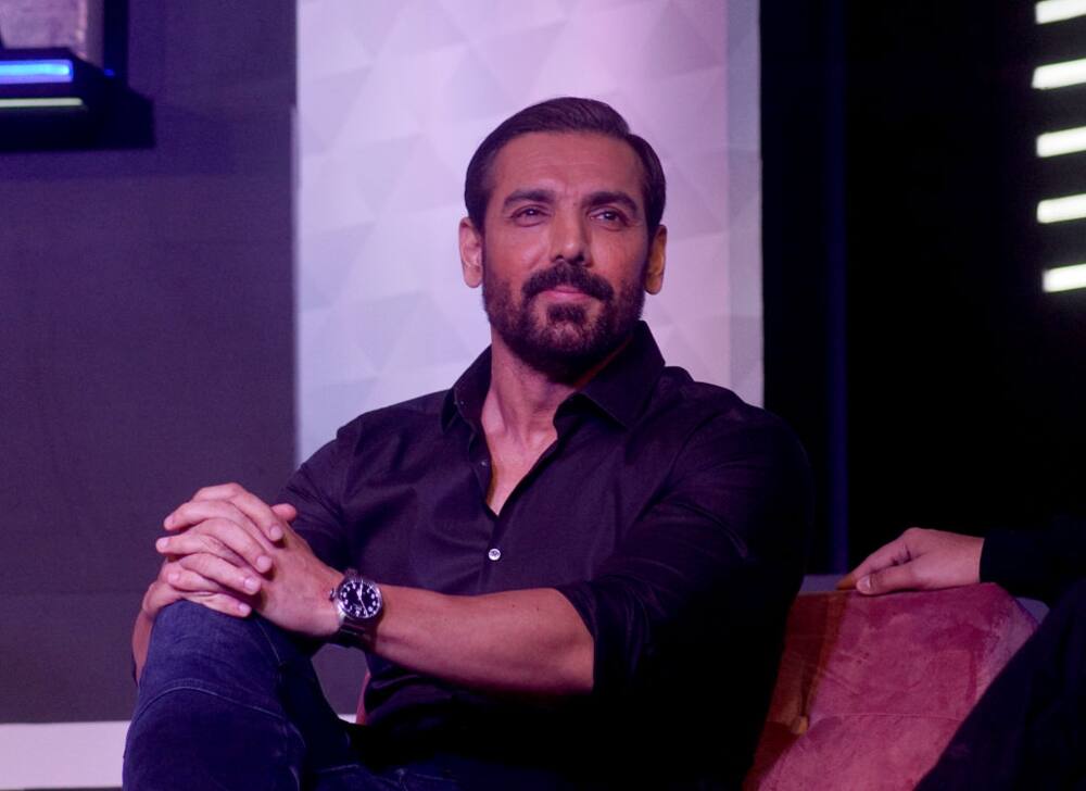 John Abraham posed on a chair and looked on