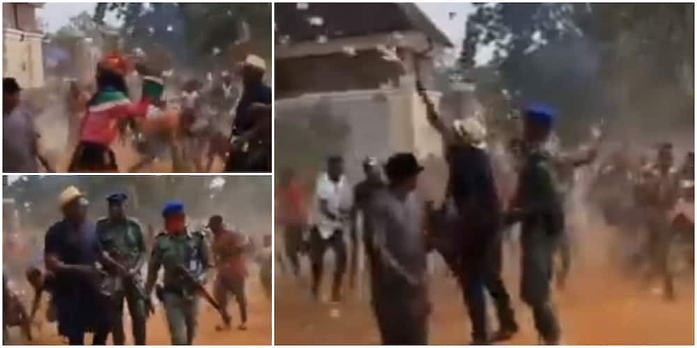 Reactions as masquerade, others jostle to pick cash as man sprays money on street in video