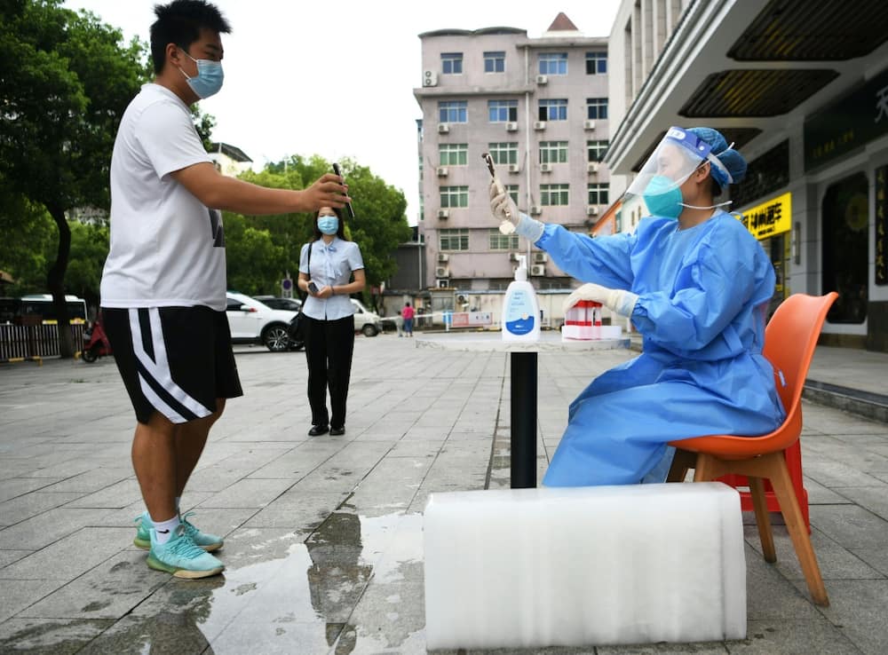 A health worker preparing Covid tests sits next to a block of ice in an attempt to cool off as China bakes under record temperatures