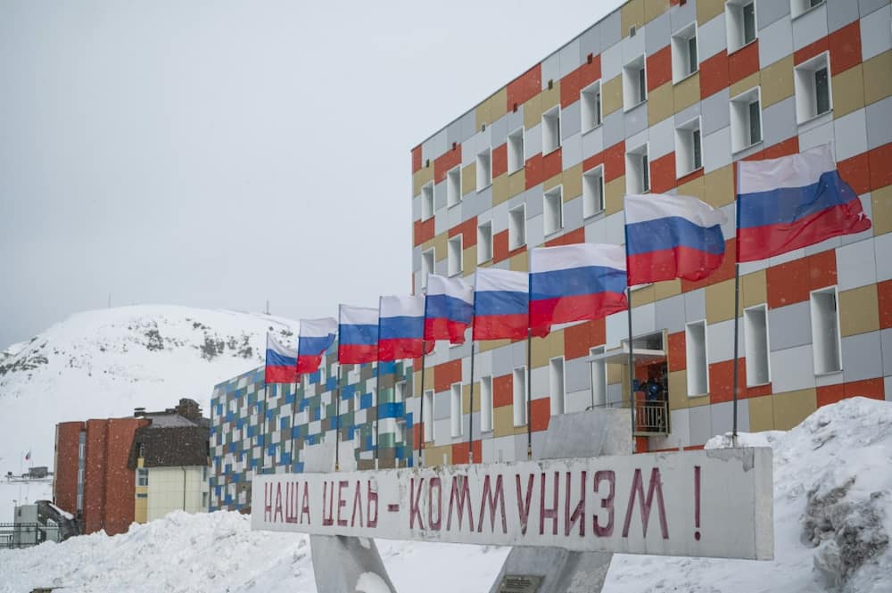 A sign in Russian declares 'Communism is our goal!' before a bank of Russian flags in Barentsburg, a Russian mining settlement on Spitsburgen