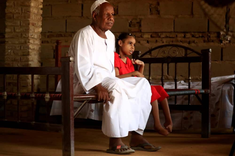 Nafisa, 8, who is unable to walk, is pictured sitting next to her father in the village of Banat