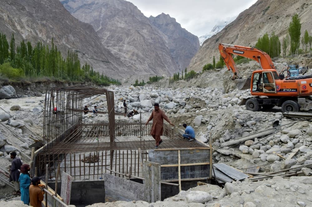 Construction workers build a temporary bridge in Hassanabad after the village's main bridge was destroyed in the flood