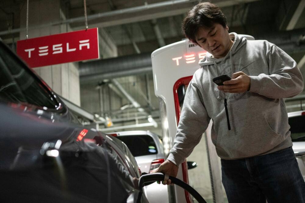 Atsushi Ikeda, founder of a club for Tesla owners in Japan, charges his Tesla Model S at a charging station in Tokyo