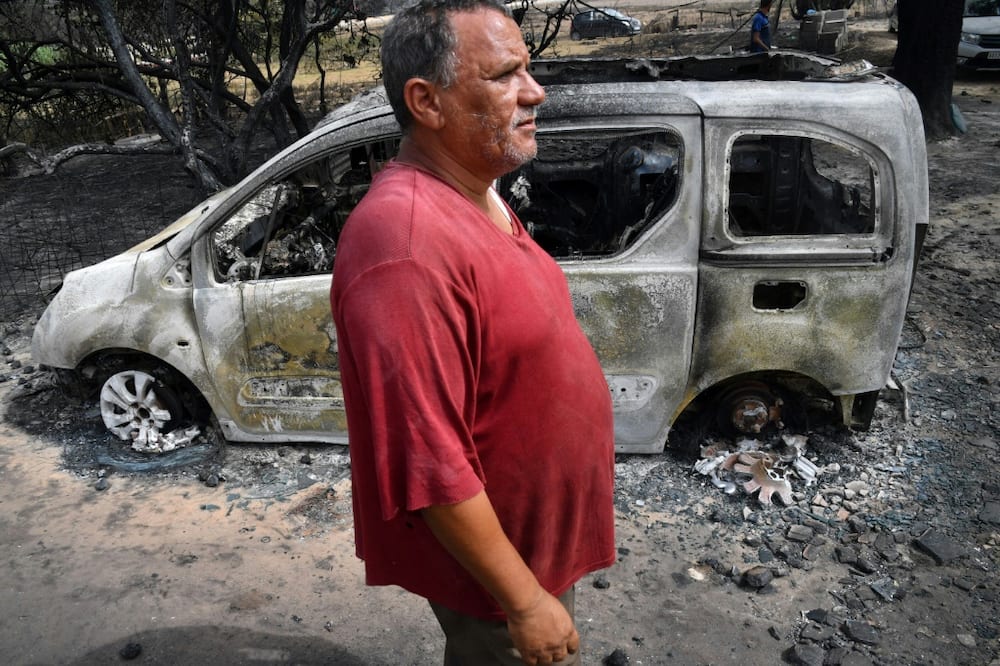 A man checks damage caused by a fire on the outskirts of the Algerian city of El Tarf, on August 18, 2022