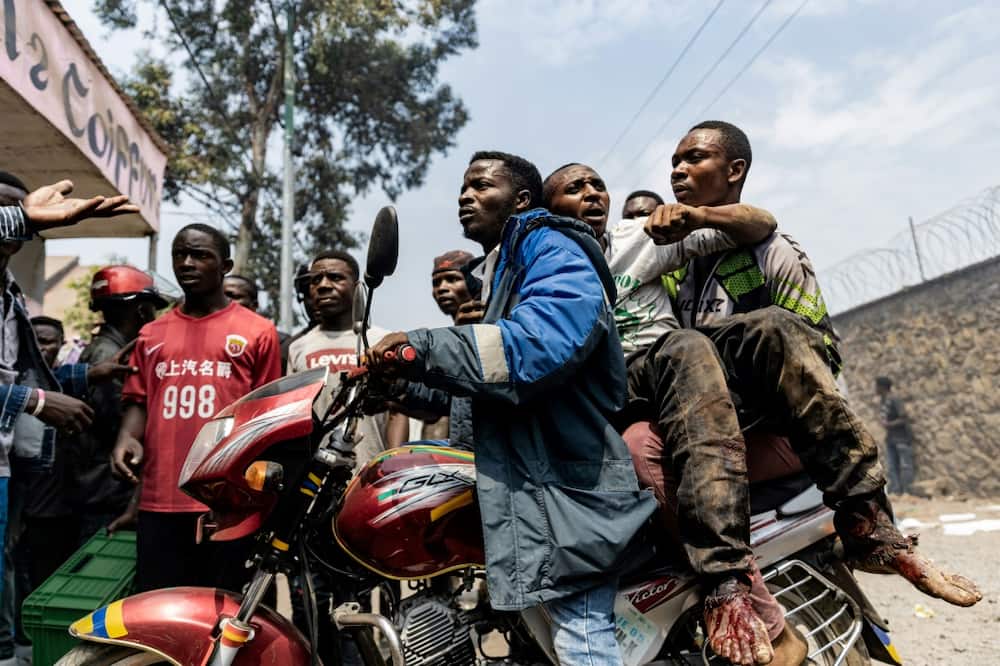 An injured man was taken away on a motorbike during Monday's protests at the UN's warehouse in Goma