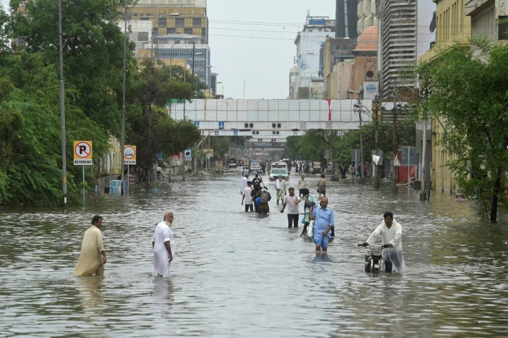People wade across a flooded street in Karachi