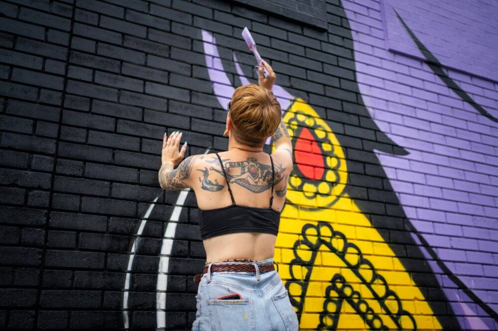 Nikki, an assistant of the artist Hatecopy, paints on a wall during the Mural festival in Montreal, Quebec on June 16, 2022