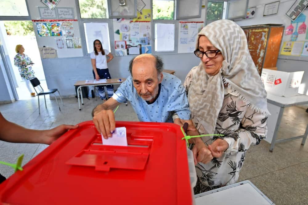An elderly Tunisian man arrives with his wife to vote in Tunis in a referendum on a draft constitution