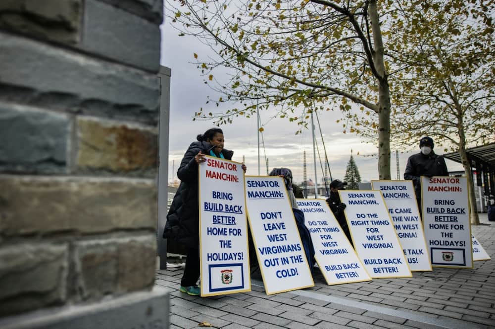 Activists with the Center for Popular Democracy hold signs near the entrance where Senator Joe Manchin's boat is docked in Washington in December 2021