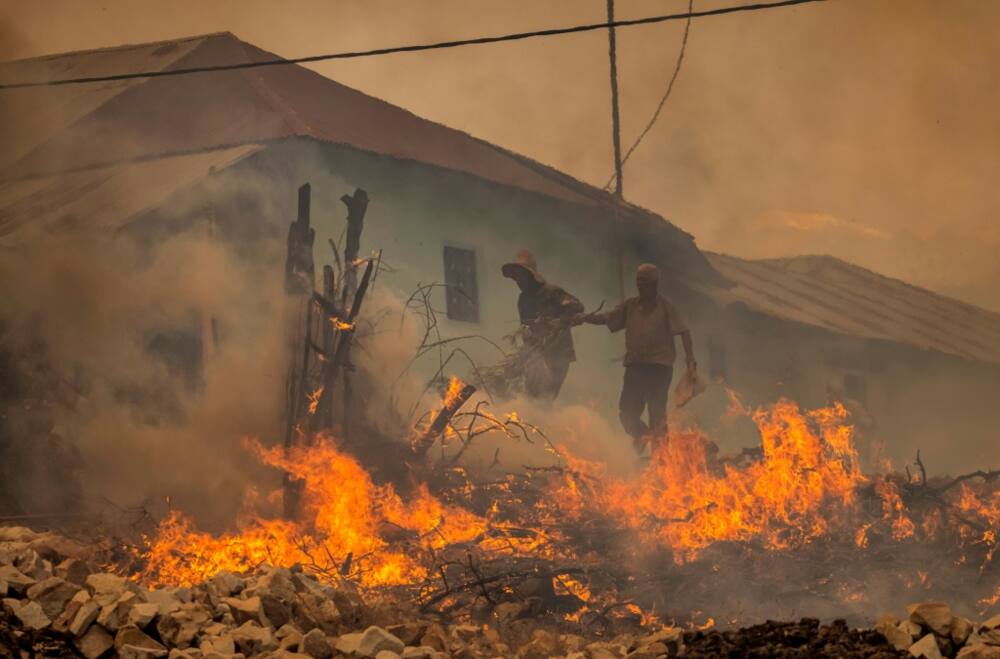 Two men evacuate from a village as forest fires rage near the Moroccan city of Ksar el-Kebir on Thursday