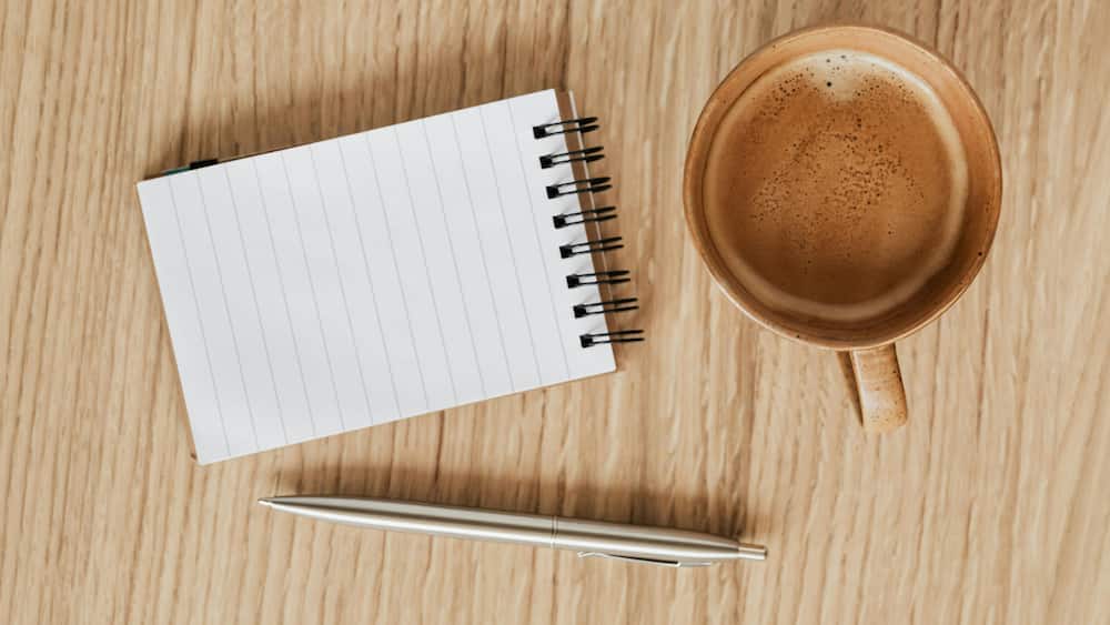 A blank notebook with a pen and coffee.