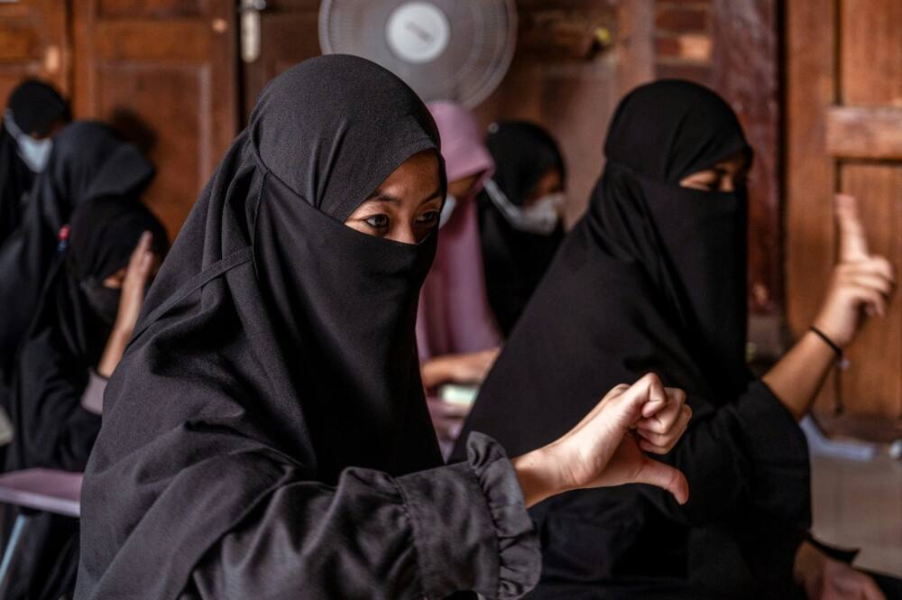 Girls in conservative Islamic dress practice sign language in a class 100 metres from the boys