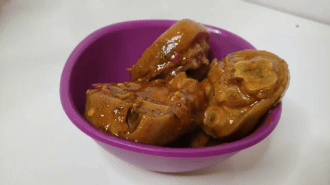 Serving cooked pig's feet in a bowl.