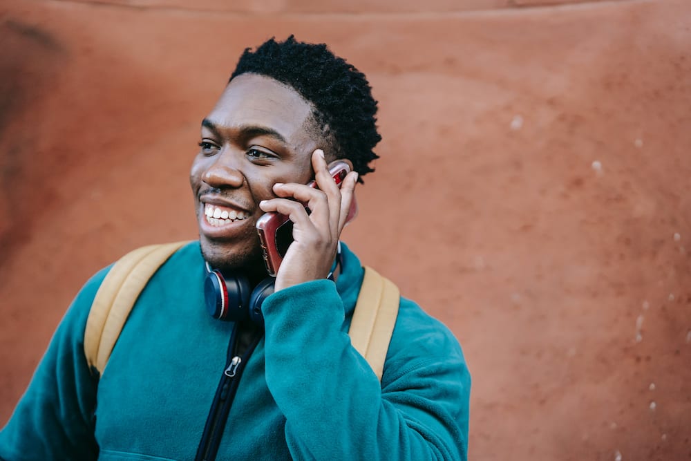 A happy man in a blue jacket making a phone call