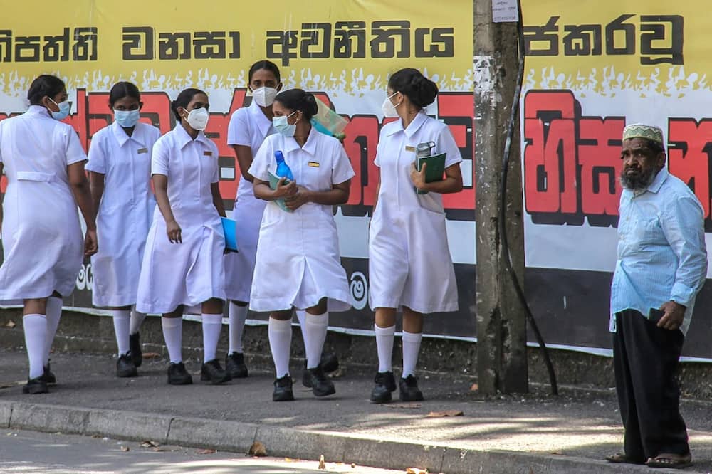 Nurses walk outside the National Hospital in Colombo, where many of its 3,400 beds are lying unused