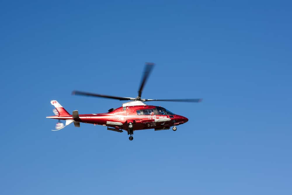 A red and white helicopter flying in the blue sky