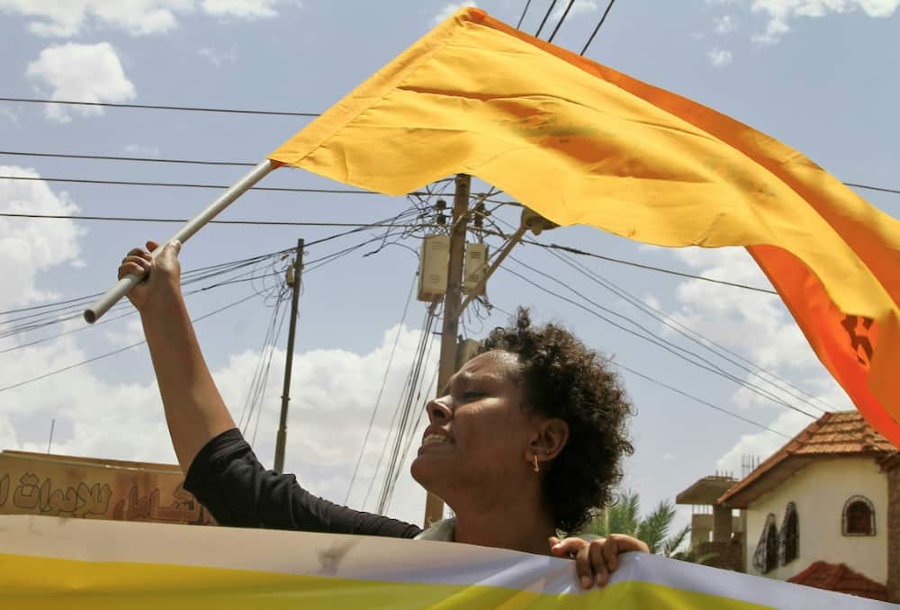 A Sudanese woman raises a flag during a pro-democracy rally in the capital Khartoum