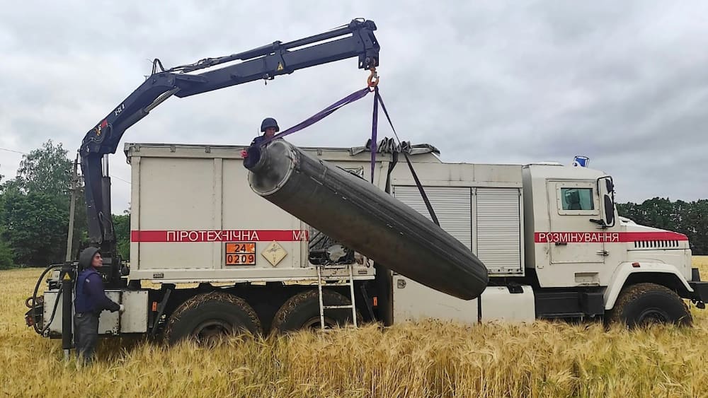 A crane lifts part of an unexploded missile from a a wheat field in UKraine's Mykolaiv region, as a deal is due to be signed tounblock grain exports