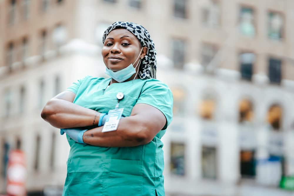 A smiling female medic in green scrubs