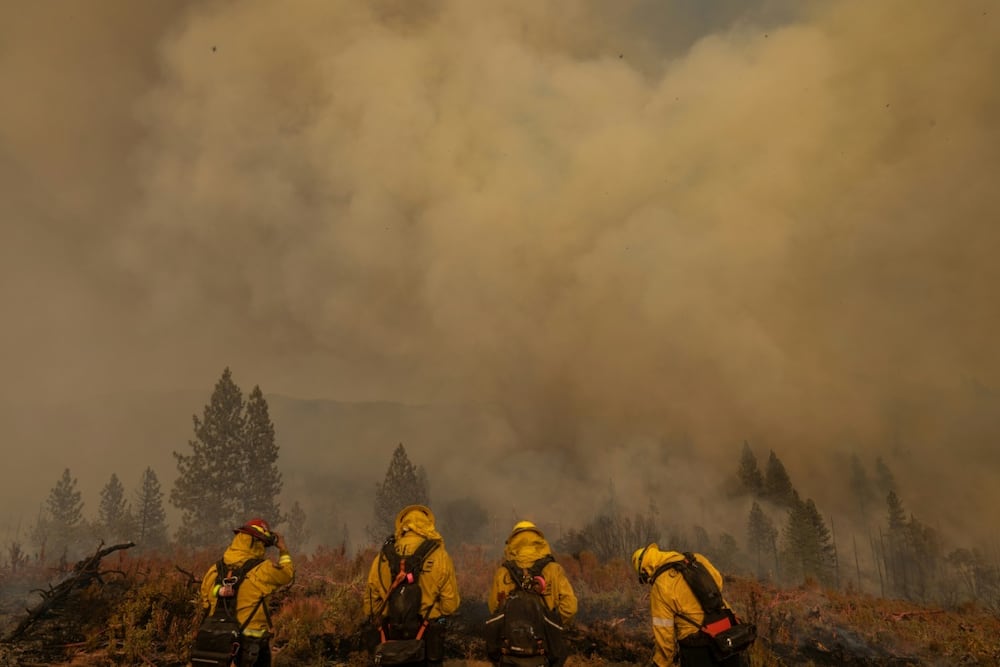 Smoke rises behind firefighters at at the Oak Fire in Mariposa, California
