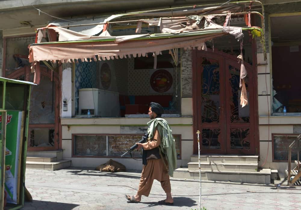 A Taliban fighter stands guard in front of a Sikh temple following the attack in Kabul