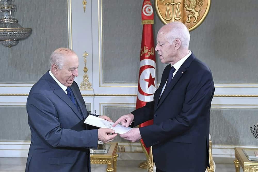 Sadeq Belaid hands a draft of the new constitution to President Kais Saied (R) at the Carthage Palace in Tunis on June 20 last month