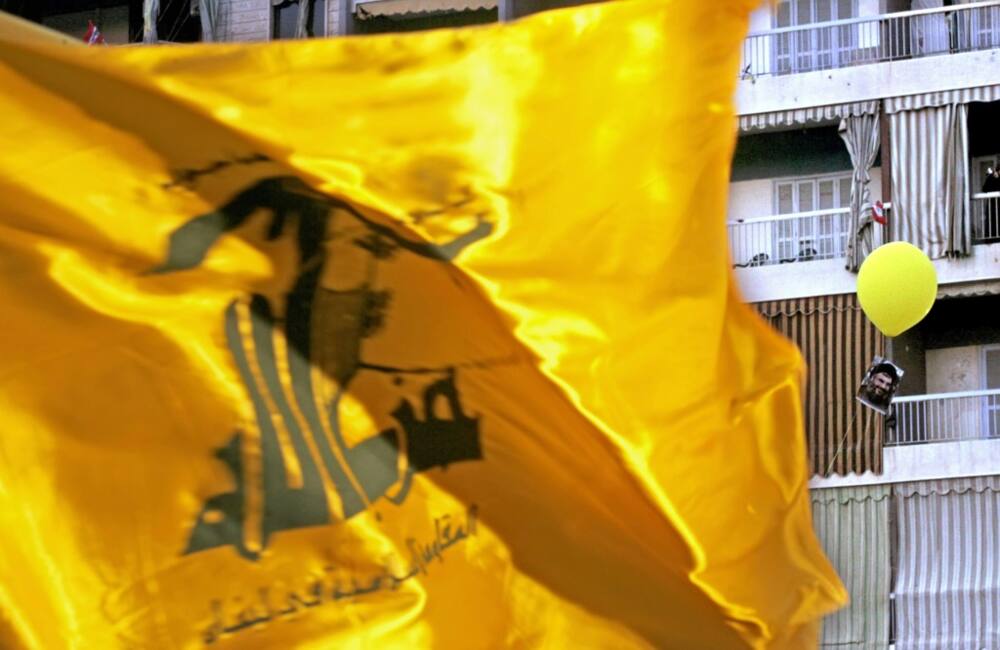 A Hezbollah flag flutters over a ceremony to mark the first anniversary of the war with Israel in Beirut's southern suburb of Dahiyeh, on August 14, 2007, while a portrait of Hezbollah chief Hassan Nasrallah tied to a balloon floats behind