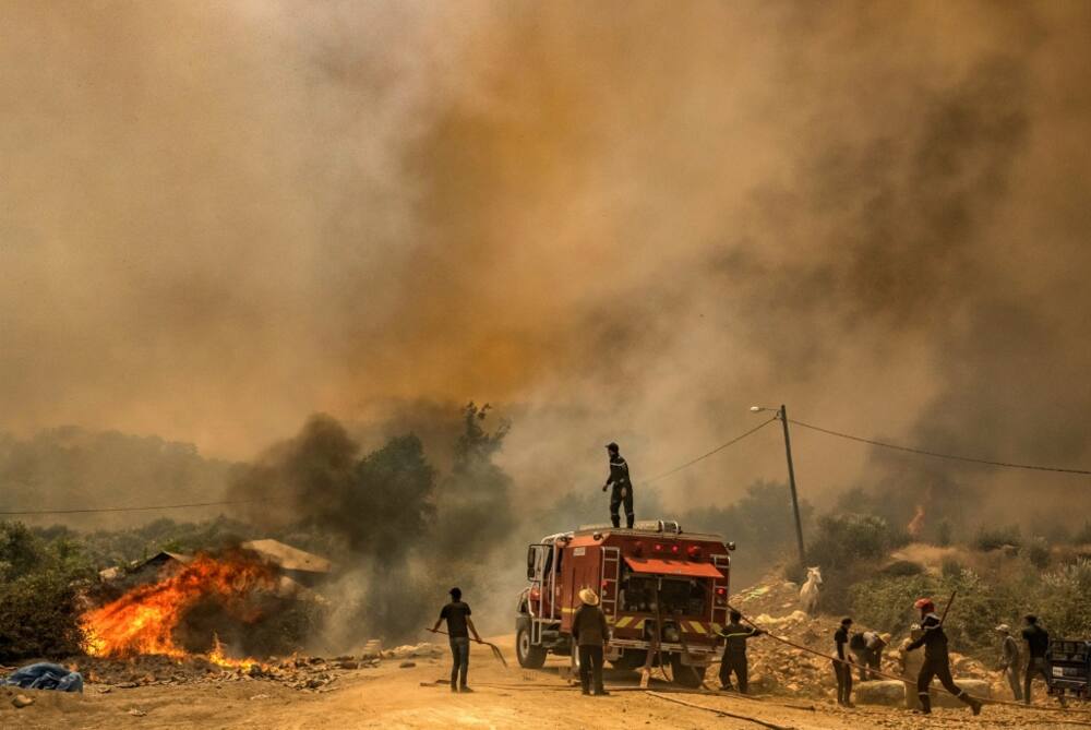 Firefighters battle a blaze raging in Morocco's northern region of Ksar Sghir on July 14