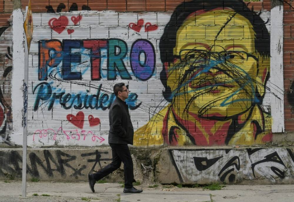 A man walks past a mural depicting Colombian left-wing presidential candidate Gustavo Petro in Bogota on June 16, 2022, ahead of the weekend's presidential runoff election