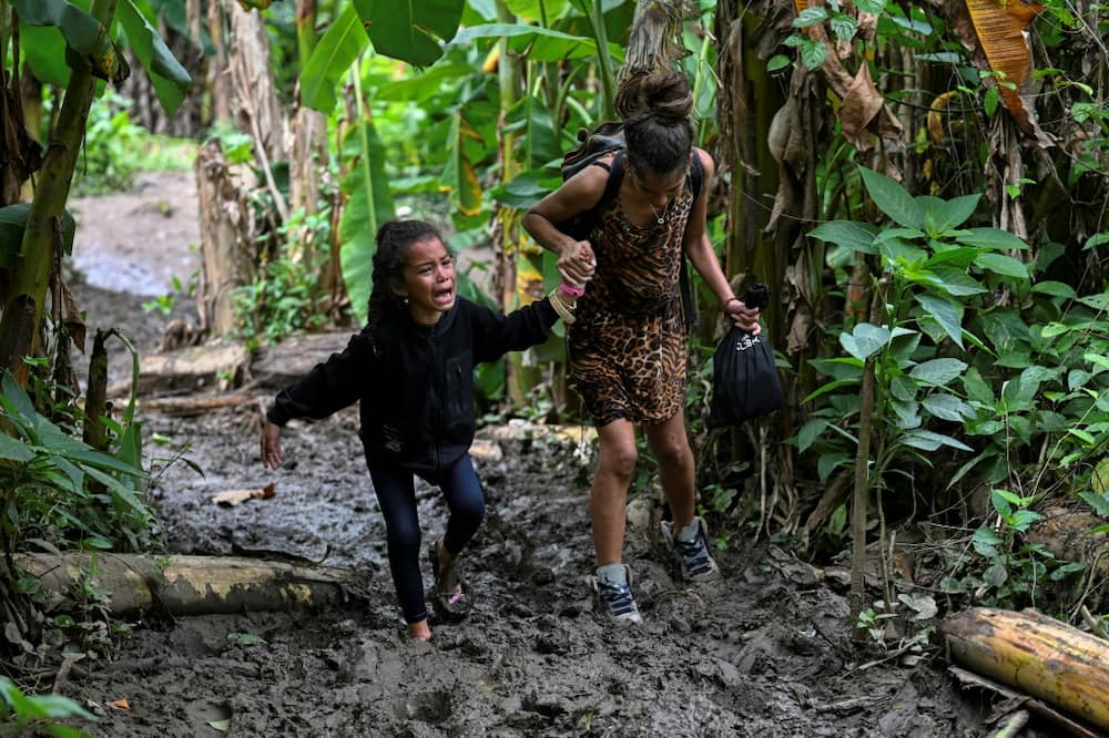 A Venezuelan migrant girl is helped by her mother as they arrive at Canaan Membrillo village in the Darien Jungle