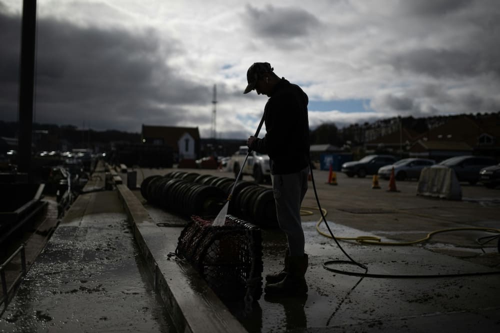 Deck hand Ben Hinchley cleans lobster pots before heading out to sea off Whitby