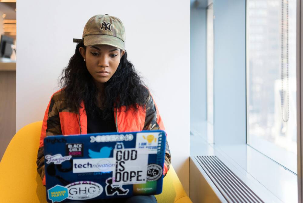 A young woman in a cap is using a laptop