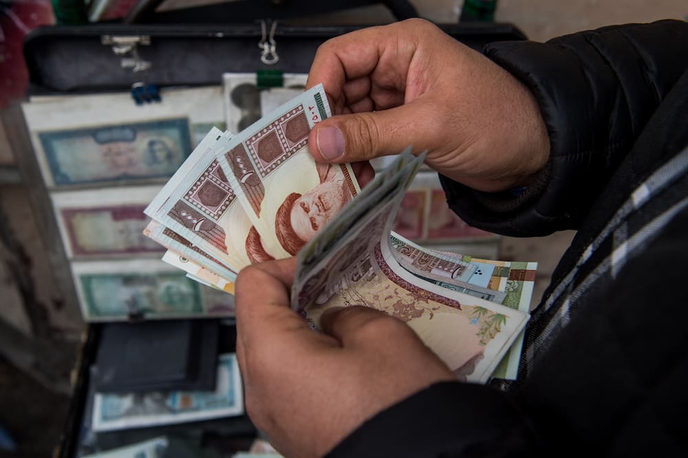 A currency trader counts Iranian rial banknotes at a money exchange market