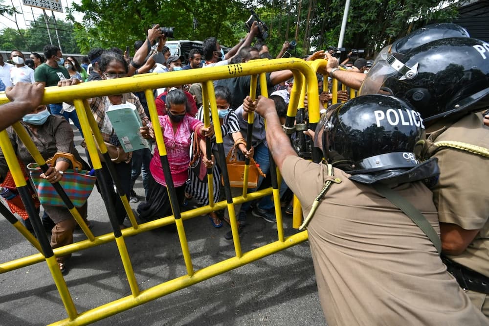Opposition activists try to overturn a police barricade during a protest in Colombo on June 22, 2022