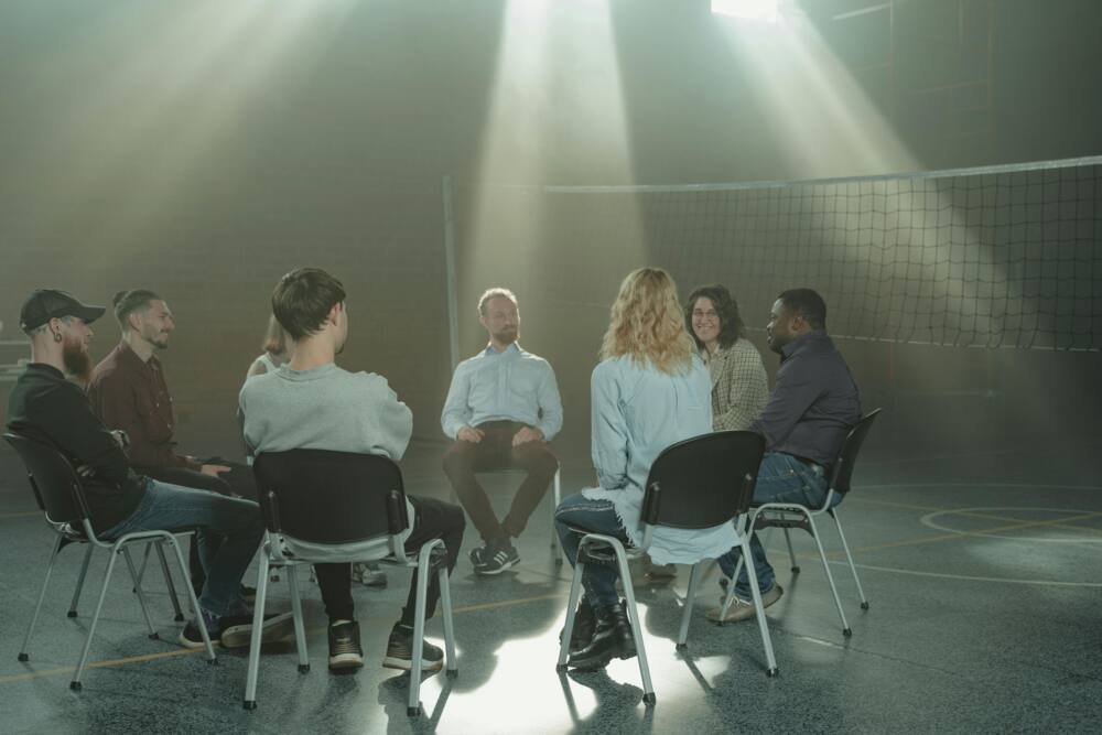 A group of people sitting on chairs in a circle inside a room