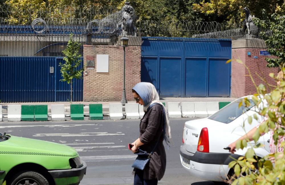 In this file photo taken on August 21, 2015, an Iranian woman walks past the then closed British embassy in the capital Tehran