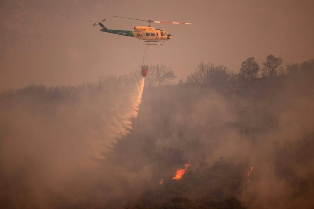A helicopter douses a wildfire in Spain's Malaga province on July 15
