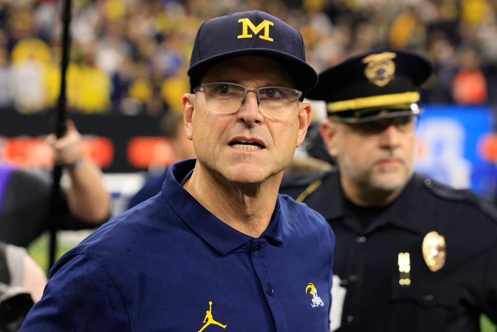 Jim Harbaugh of the Michigan Wolverines walks on the field after winning the Big Ten Championship