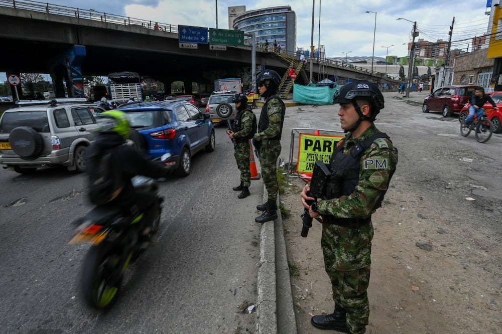 Soldiers stand guard at a checkpoint on a road entering Bogota, on June 18, 2022, a day before the presidential runoff election