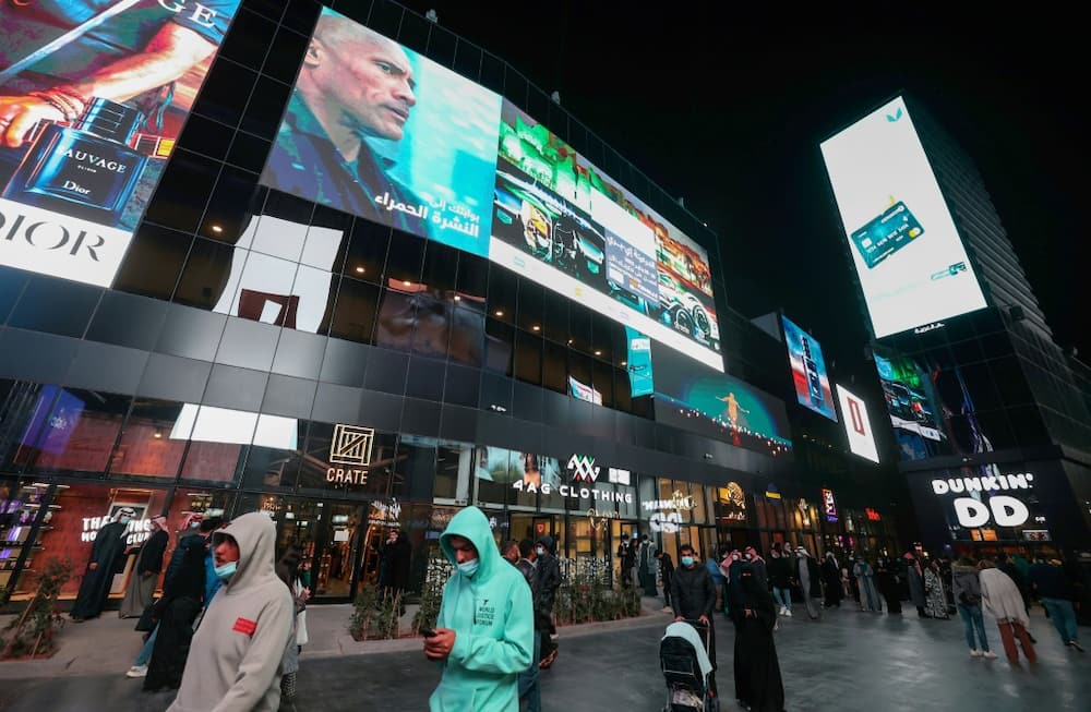 People walk beneath advertising billboards at Boulevard entertainment city in the Saudi capital Riyadh -- several analysts said the kingdom's youth are more open to ties with Israel
