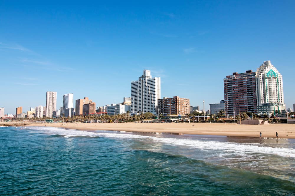 The ocean and beach against Golden Mile coastal city skyline and blue sky in Durban