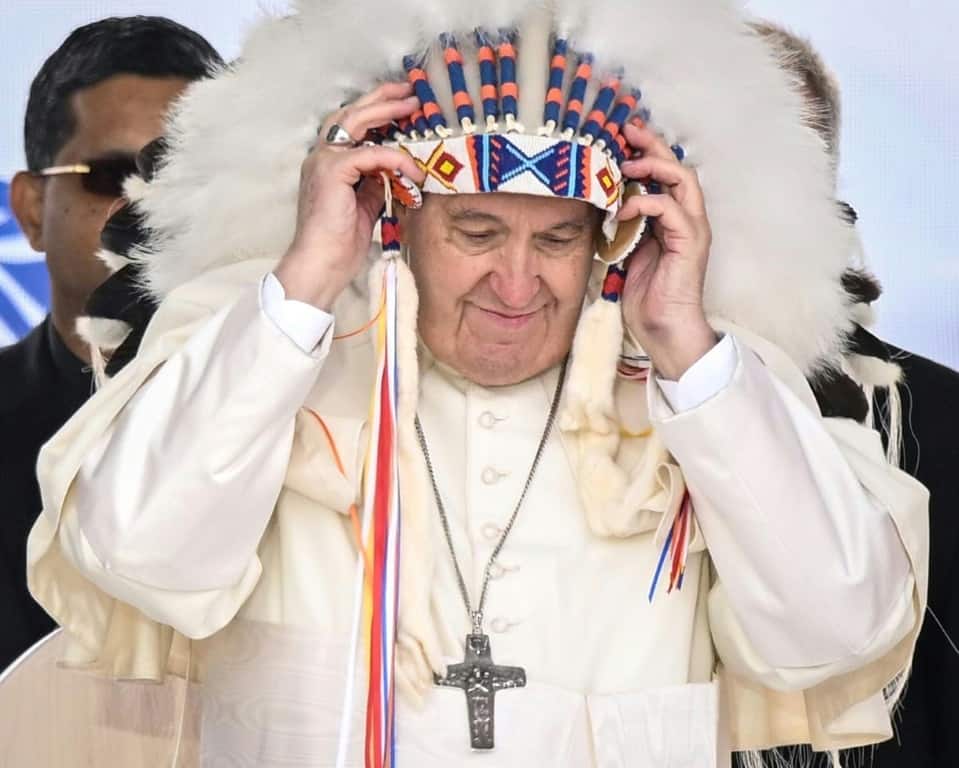 Pope Francis wears a headdress presented to him by an Indigenous leader during a meeting at Muskwa Park in Maskwacis, Canada on July 25, 2022
