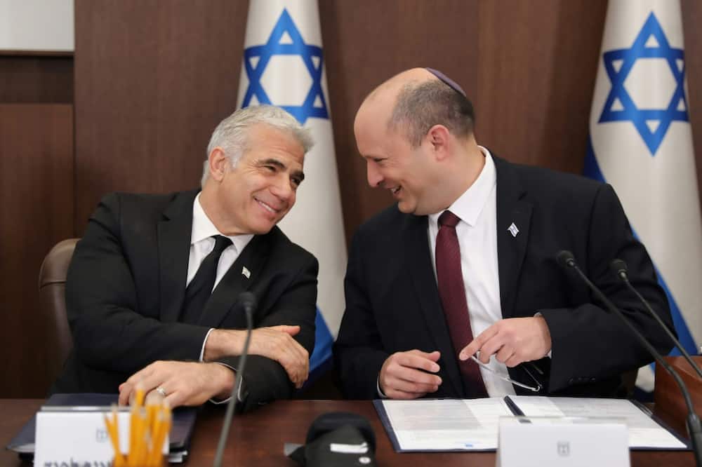 Israeli Prime Minister Naftali Bennett (R) speaks with Foreign Minister Yair Lapid (L) during a cabinet meeting in Jerusalem,