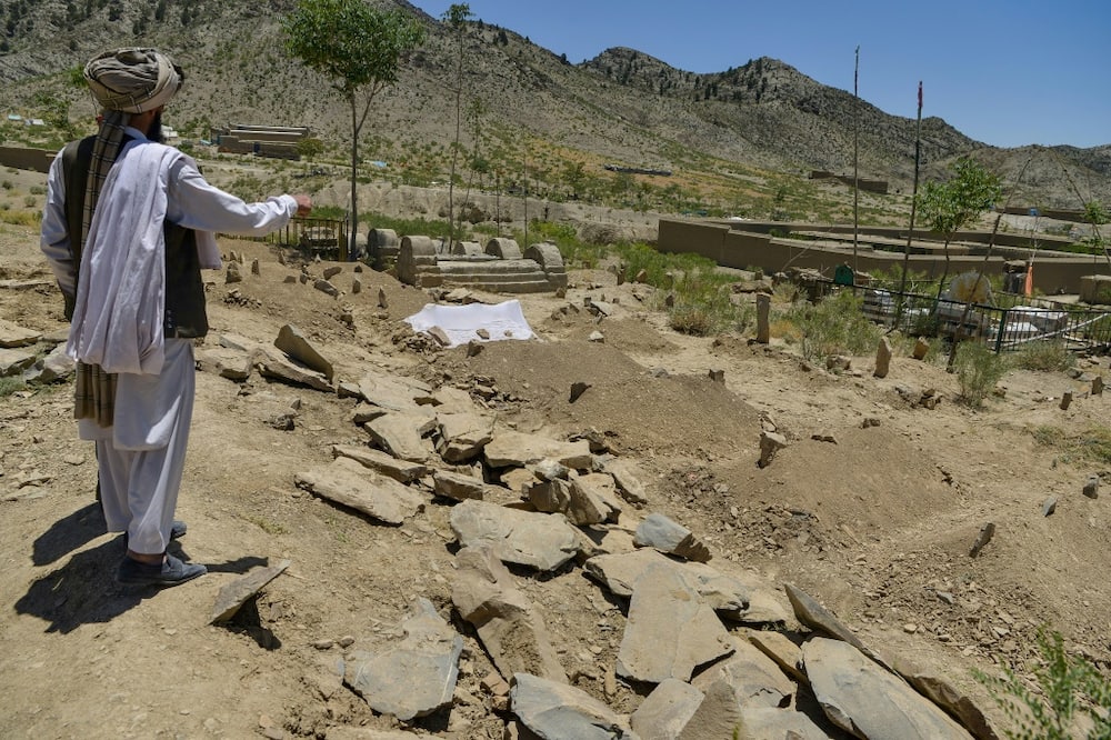A villager looks over freshly dug graves containing victims of the deadly Afghan earthquake in Gayan district