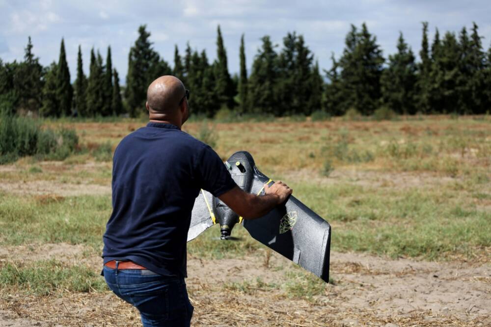 A technician from the RoboCare startup company prepares to fly a drone over an agricultural area